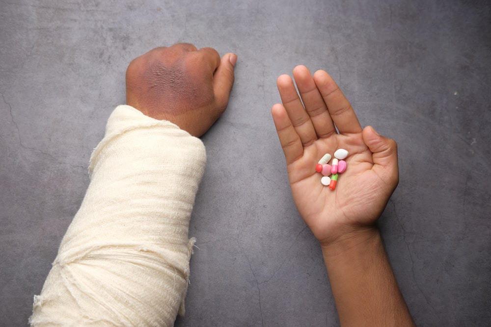 A patient with a cast various medicines in another palm